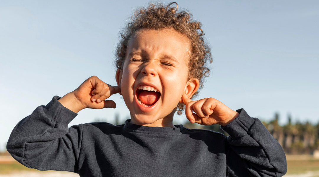 Niño tapándose los oídos Niño tapándose los oídos